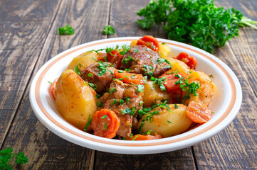 Roast turkey, potatoes, carrots and fresh parsley in a bowl on a wooden background