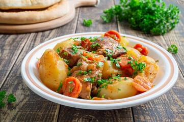 Roast turkey, potatoes, carrots and fresh parsley in a bowl on a wooden background