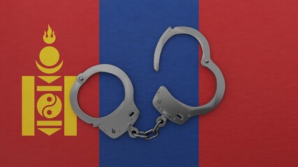 A half opened steel handcuff in center on top of the national flag of Mongolia