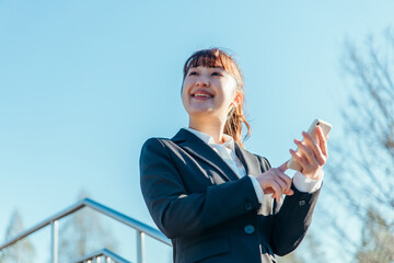 スマホを使うビジネスウーマン（笑顔）
