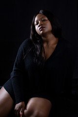 Fototapeta premium Beautiful happy black woman in a sultry pose on a black background