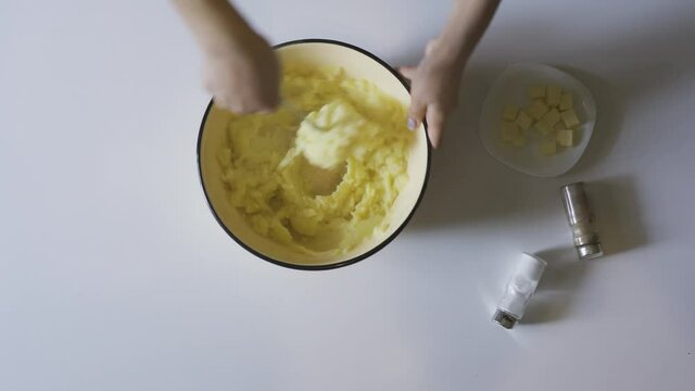 An overhead view of a female hand preparing mashed potatoes in 4K