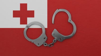 A half opened steel handcuff in center on top of the national flag of Tonga