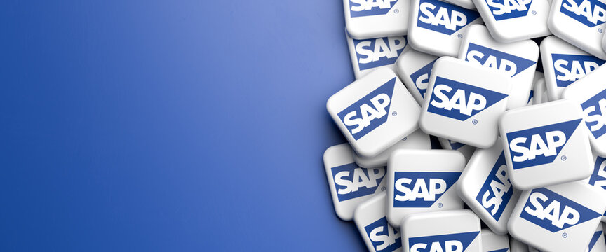 Logos of the tech company SAP on a heap on a table. Copy space. Web banner format.