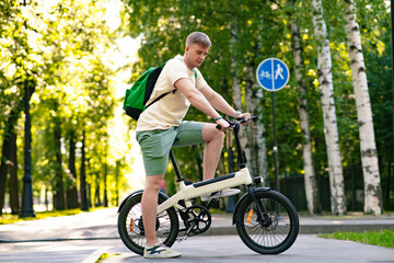 Young guy riding an electric bicycle, bike in a summer park. Active lifestyle, sports