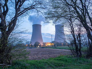 Branch with green leaves  against nuclear power plant.