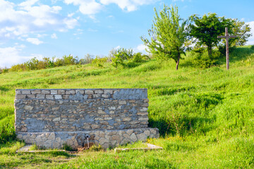 Fresh mineral water from a natural water source . Source of groundwater . Cross on the hill near...