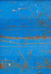 Close-up of a weathered sheet metal plate painted in blue. Paint is partly peeled off revealing...