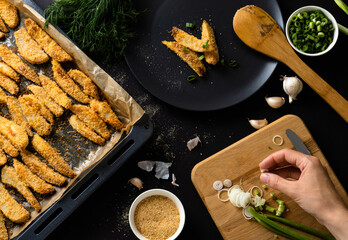 Top view of homemade baked potatoes on baking sheet placed on the dark background. Cooking process concept.
