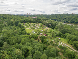 Fototapeta na wymiar Low-rise settlement among green deciduous forest. Aerial drone view.
