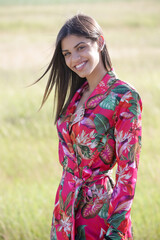 Outdoor portrait of gorgeous teenage girl in bright floral dress on meadow