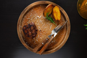 filet mignon medium rare served on a wooden plate with baked potatoes