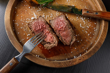 filet mignon medium rare served on a wooden plate with baked potatoes