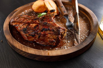 medium rare Steak on bone Veal rib with potato on a wooden plate