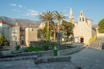 Fototapeta na wymiar Perfect view of the St. Nicholas orthodox christian church in Old Town Budva in Montenegro on a sunny day next to palm trees