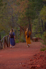 two young blonde women with dresses walking in the forest at sunset people walking in the forest