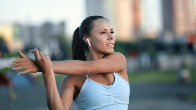 Happy young fitness woman warming up training outdoor at sunset cityscape enjoying healthy lifestyle