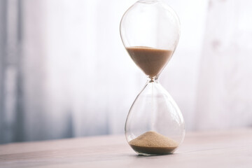 hourglass on table, sand flowing through the bulb of sandglass