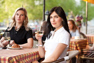 Beautiful young brunette woman at cafe drinking white wine. Communication and friendship concept