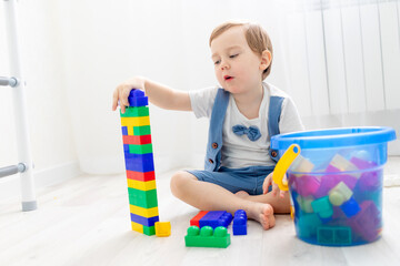 a child with a constructor at home, a cute boy plays or collects a colored constructor