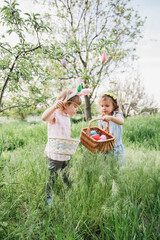 Group Of Children Wearing Bunny Ears Running To Pick Up colorful Egg On Easter Egg Hunt In Garden. Easter tradition