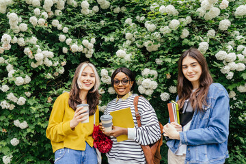 Group of international three students female friends resting in campus outdoors during break in...
