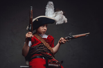 Fototapeta premium Little pirate aiming pistols against dark background
