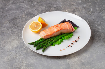 Grilled salmon fish, with asparagus,and lemon, on a white plate, horizontal no people,