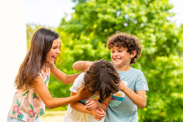 Lifestyle of three brothers smiling and playing together in a park, friends and brothers enjoying as a family, tickling each other