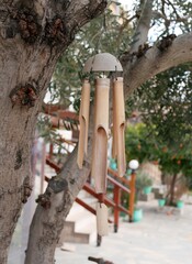 Wind chimes made of bamboo hang from a tree on a sunny spring day. Homemade percussion musical instrument in the yard of the house.