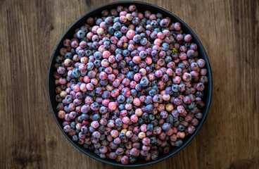 Organic blueberries ripe and unripe. In a big black bowl on wooden table.