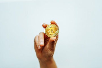 Bitcoin in hand on a light background.