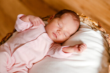 Cute newborn baby in pink jumpsuit sweet sleeps. View from above.