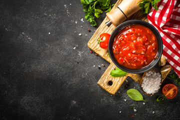 Tomato sauce in a bowl with spices, herbs and fresh tomatoes. Top view with copy space.
