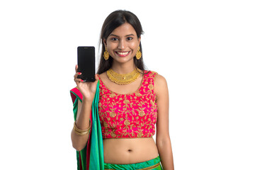 Young Indian traditional girl using a mobile phone or smartphone and showing blank screen smart...