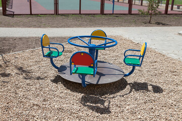 Swing carousel on an empty playground for children in the courtyard of a new apartment building, no...