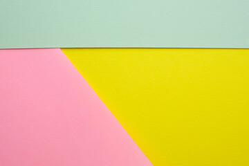Abstract colored background made with three pieces of cardboard top view. Segmented background of green, yellow and pink. Different colors paper background.