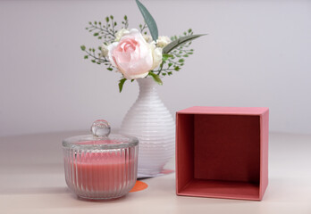 Pink scented candle in a glass candlestick and vase with a flower.
