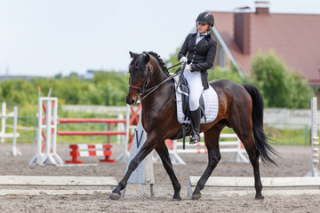Young sportswoman riding horse on advanced dressage test during the equestrian competition