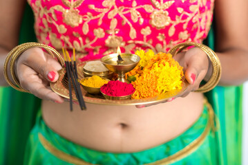 Beautiful Indian young girl holding pooja thali or performing worship on a white background