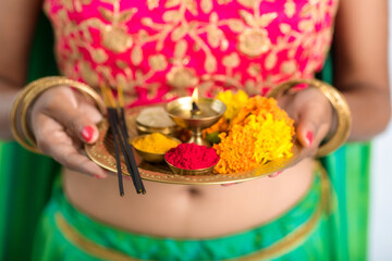 Beautiful Indian young girl holding pooja thali or performing worship on a white background