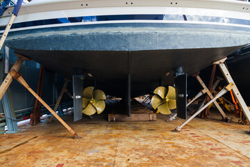 Aft with two propellers of the luxury motor yacht is dry docked on wooden blocks and supported by...