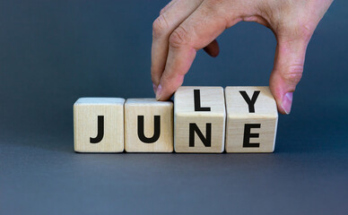 From june to july symbol. Businessman turns wooden cubes and changes the word 'june' to 'july'. Beautiful grey background, copy space. Business and from june to july concept.