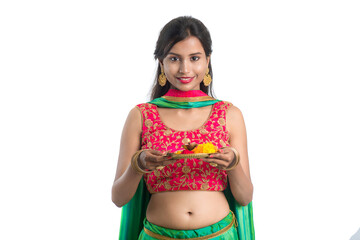 Beautiful Indian young girl holding pooja thali or performing worship on a white background