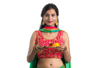 Beautiful Indian young girl holding pooja thali or performing worship on a white background