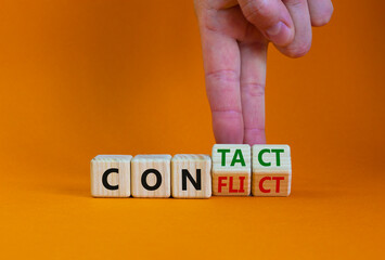 Conflict or contact symbol. Businessman turns wooden cubes and changes the word 'conflict' to 'contact'. Beautiful orange table, orange background, copy space. Business, conflict or contact concept.