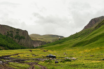 SUV with tourists rides in the mountains in cloudy weather © Андрей Комаров