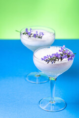 A gin cocktail with egg white foam garnished with blue flowers