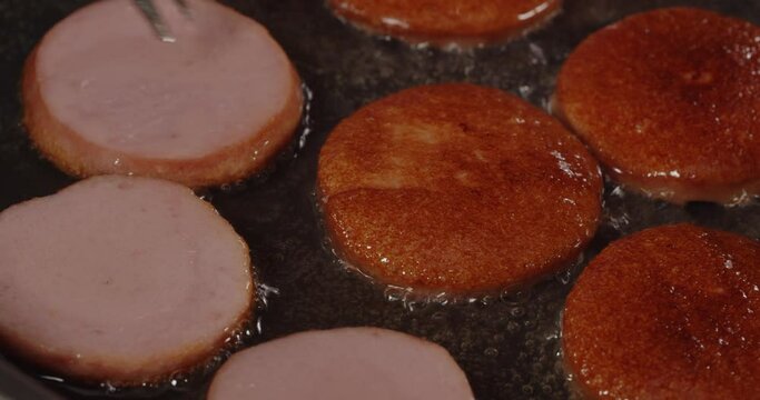 Sausages are fried in oil in a hot pan