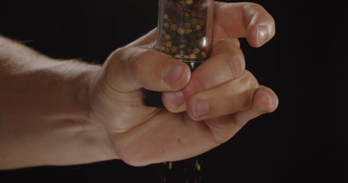 Similar spices on a black background in hand. Pepper mixture
